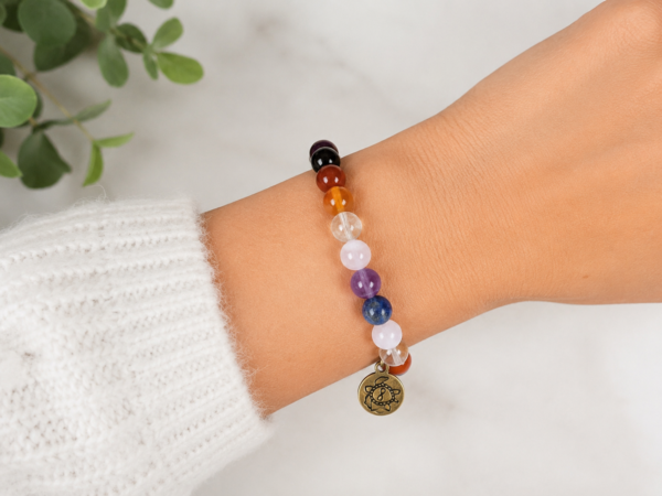Chakra intention bracelet with brass charm worn on the wrist